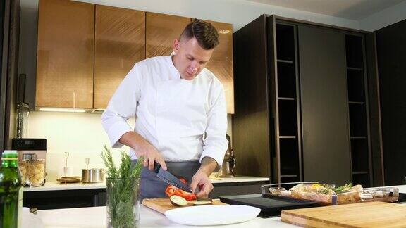 厨师在厨房的砧板上用锋利的刀切红辣椒