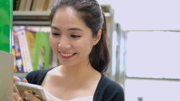 年轻的亚洲女性在图书馆用智能手机搜索