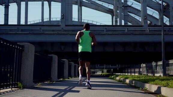 田径非洲人在绿色背心和运动短裤在桥上慢跑