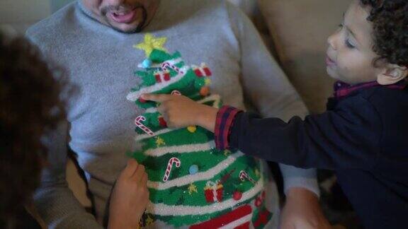 父亲在家里向儿子们展示他的圣诞毛衣