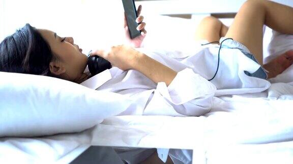 特写:美丽的女人躺在床上打着哈欠与智能手机