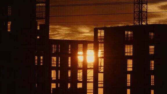 时间流逝巨大的太阳落在正在建造的建筑后面阳光透过多层建筑的窗户