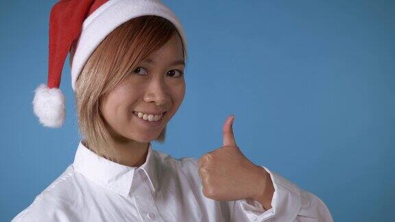 漂亮的女孩圣诞帽显示拇指向上