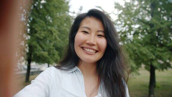 肖像快乐的亚洲女孩在绿色公园做视频通话微笑交谈
