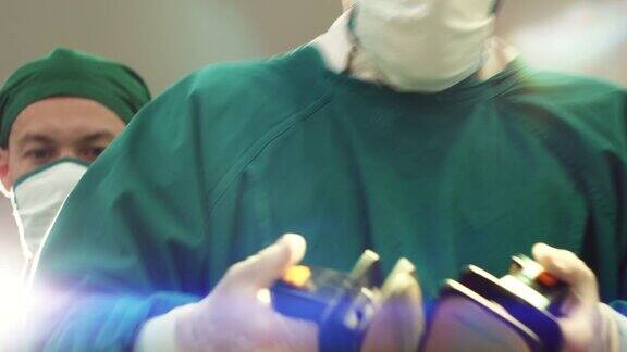 外科医生小组使用除颤器电击亚洲男性病人