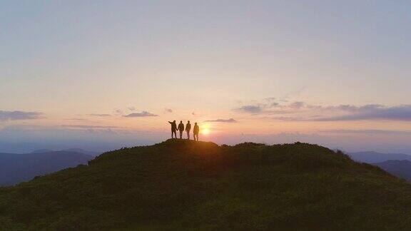 四个朋友站在美丽的夕阳下的山上