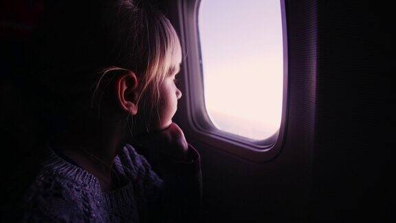 女孩坐在飞机上看着窗外冉冉升起的太阳