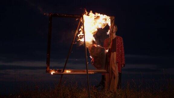 黄昏时分年轻的艺术家站在一个燃烧着的画架前