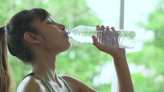 年轻健康的女人喝着塑料瓶里的水