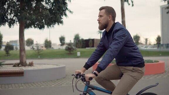 夏日里一个留着胡子的英俊男子在城市公园里骑自行车