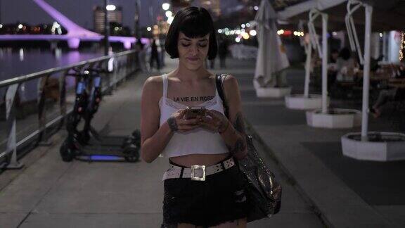 拉丁纹身女人在户外使用智能手机