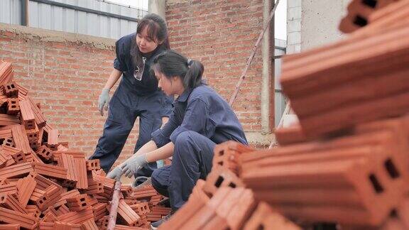 亚洲两个十几岁的女孩志愿工作一起建设一个住房项目青少年活动
