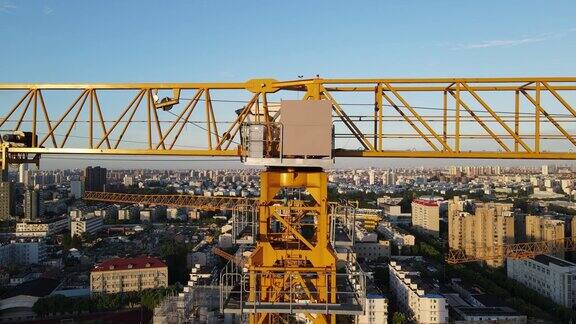 日落时分无人机镜头移动到建筑工地的吊车塔上