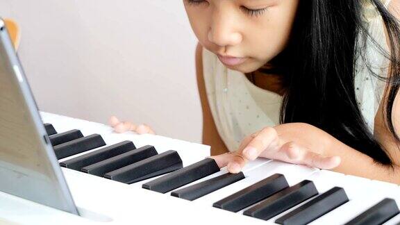 特写亚洲小女孩学习钢琴与学习弹钢琴在家
