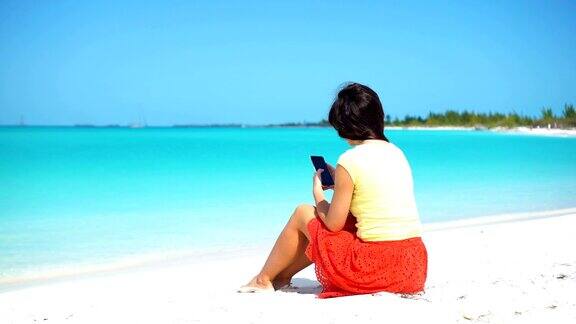 年轻女子在热带海滩度假期间使用电话游客使用手机