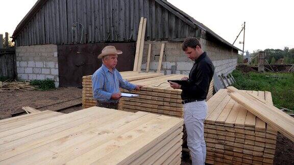 工人和商人在锯木厂检查计数访问由木板包装