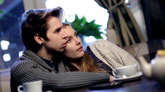 相爱的年轻情侣在咖啡馆休息时拥抱在一起