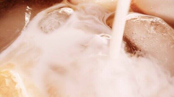 将奶油或牛奶倒入冰咖啡、冰茶、冰乐、冰乐冰块中