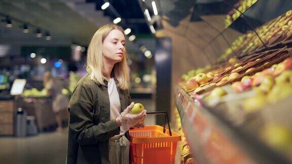 年轻的金发女人在超市的柜台上挑选水果和蔬菜女主妇站在菜市场旁购物