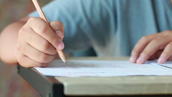 教育考试在大学或高中:手持铅笔的学生测试试卷上的答案在校园教室填写试卷知识学习