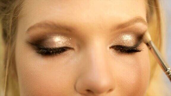 化妆师将明亮的基本色眼影涂在女孩的眼睛上