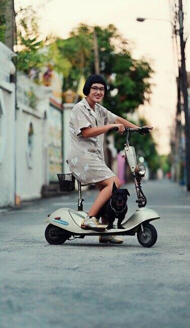 在城市里骑着电动车的女人和她的狗