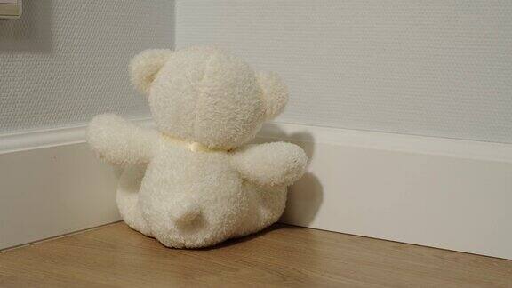 白色毛绒熊玩具坐在房间的角落里