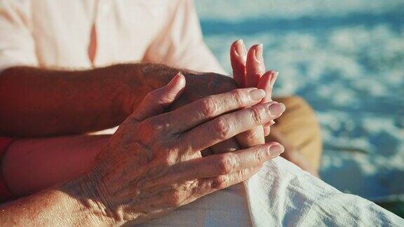 在海滩上牵手的老年夫妇的腹部