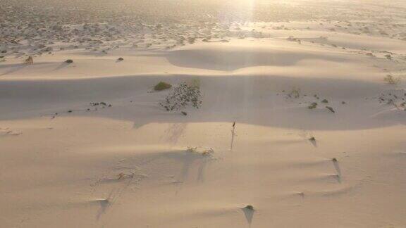 无人机拍摄到一个女人在日落时分独自行走在沙漠中