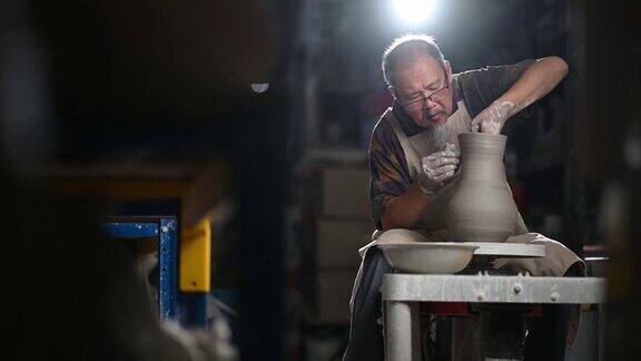 亚洲华人高级泥塑艺术家工作在他的工作室与纺织陶轮