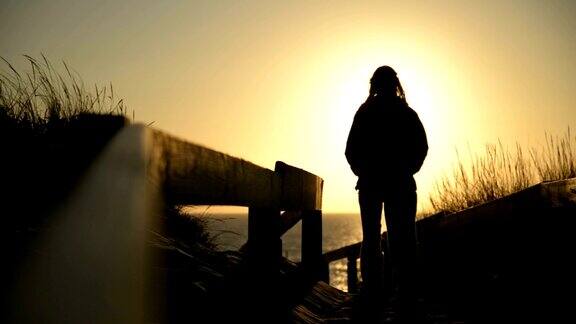 日落时分年轻女子漫步在海边