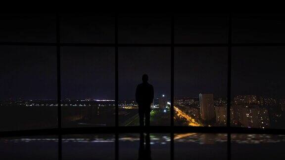 在城市闪电背景下站在窗边的男子