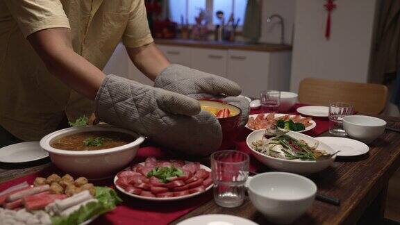 一名戴着防护手套的男子在餐桌上端着热汤准备在家里吃年夜饭