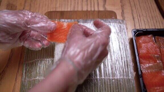 一位专业厨师在厨房柜台上为虾寿司卷添加了三文鱼片在一家日本餐厅男厨师正在准备一个鲑鱼和虾寿司卷