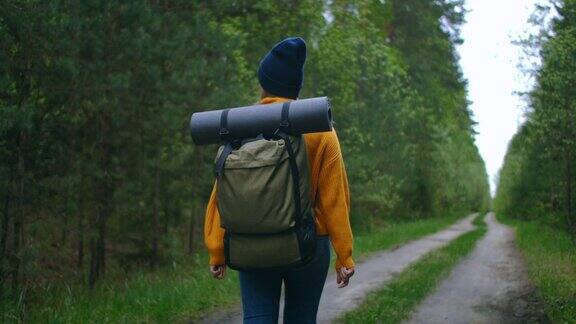 年轻女子在秋天的森林里徒步旅行