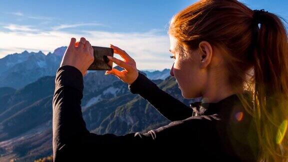 年轻女子用智能手机拍下美丽的风景
