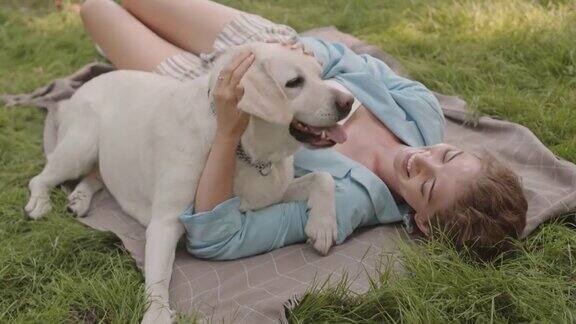 狗在草坪上舔女人的脸
