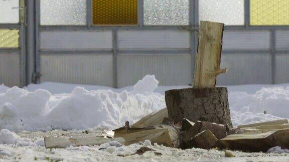 一个人在冬日村庄的雪院里砍柴的慢镜头