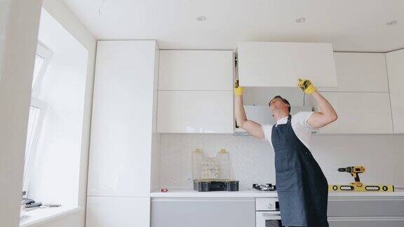 木匠在新房子里安装家具木匠修理和组装橱柜在现代厨房的白色