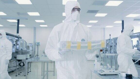 身着防护服的科学家带着成品箱通过实验室工人在设施与现代工业机械产品制造工艺:制药半导体生物技术