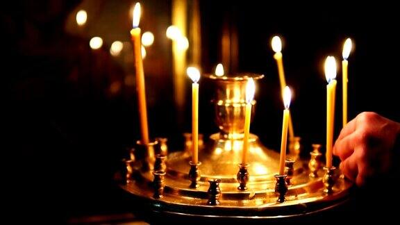 男人在东正教的烛台上纠正燃烧的蜡烛