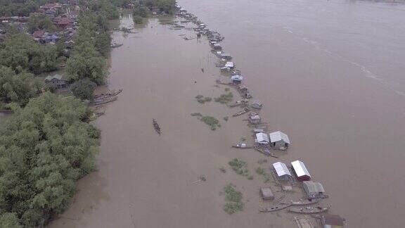 无人机拍摄:倾斜到被暴雨淹没的河岸上漂浮的房屋