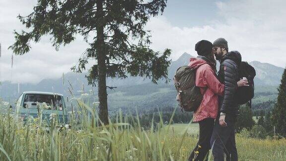 年轻夫妇在草地上拥抱山景观