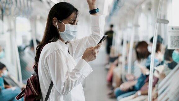 年轻的亚洲妇女戴着口罩在地铁使用电话