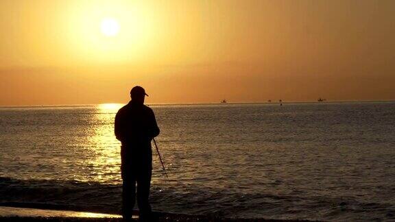 一个渔夫的剪影一个人在海上捕鱼的岩石在日落