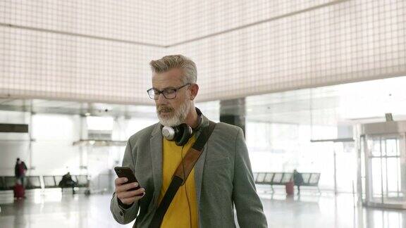成熟的商人在机场使用手机