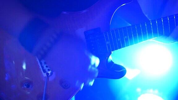 电吉他手在舞台上与彩色的蓝色风景照明