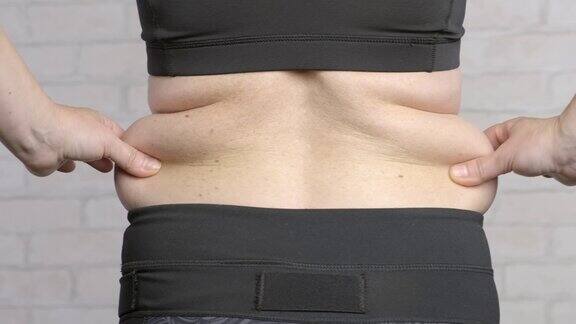 女人腰部赘肉过多女人用手从腹部和背部拉松弛的皮肤