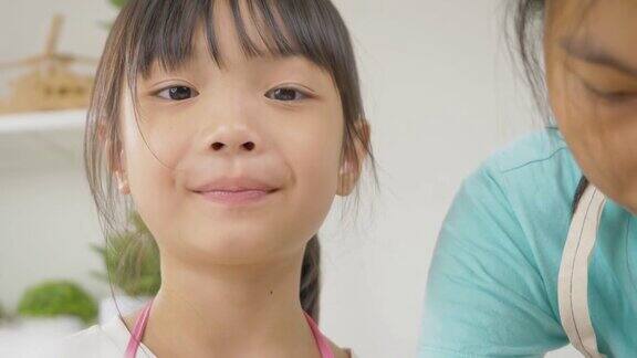 亚洲女孩舔她的手指测试甜的糖和看着她的姐姐