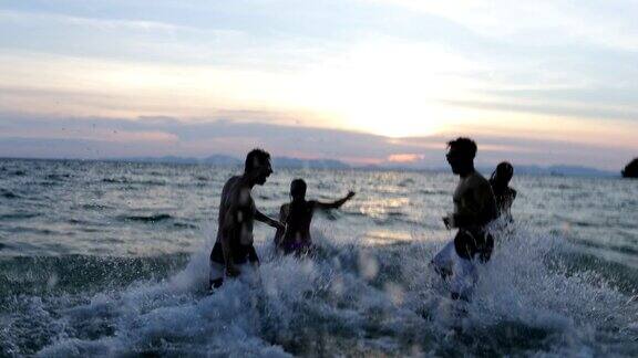 日落时分一群人在海滩上在海上奔跑溅起浪花让度假的朋友们高兴起来